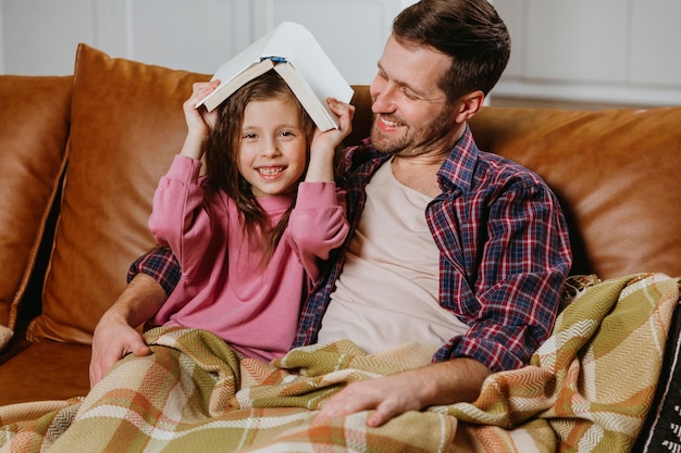 Père et fille lisant un livre à la maison ensemble