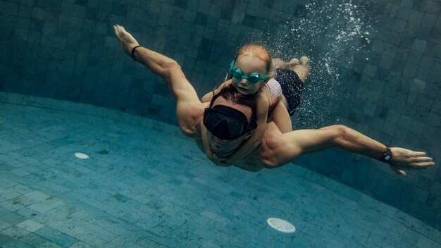 Père et fille nager ensemble dans la piscine