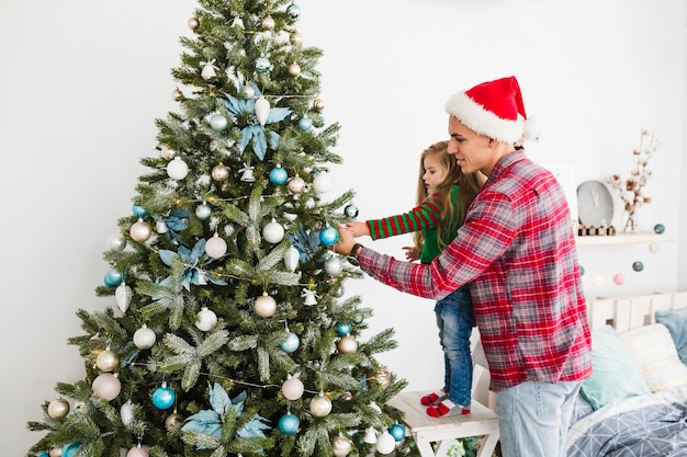 Père et fille touchant le sapin de Noël