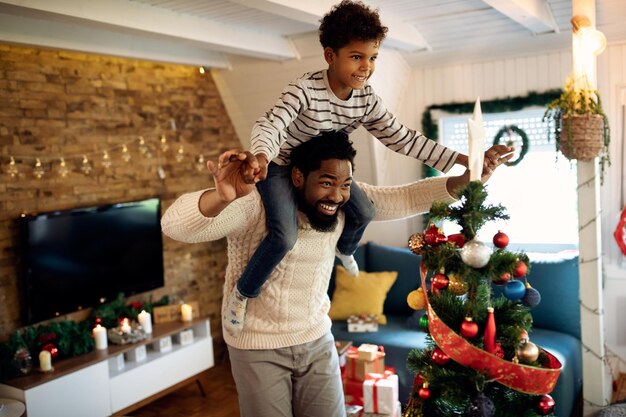 Père et fils afro-américains ludiques s'amusant à Noël à la maison