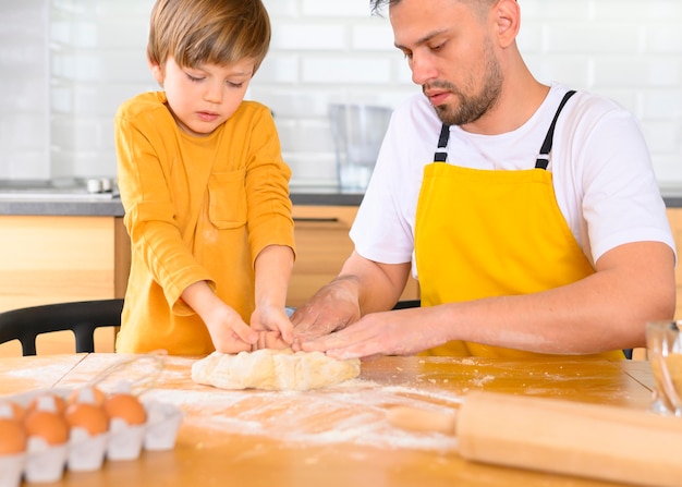 Photo gratuite père et fils, faire de la pâte dans la cuisine