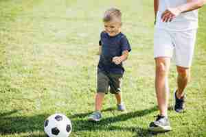 Photo gratuite père et fils jouant au football sur le terrain