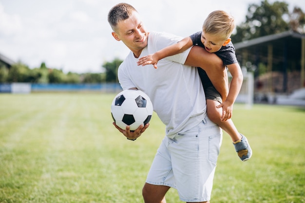 Père et fils jouant au football sur le terrain