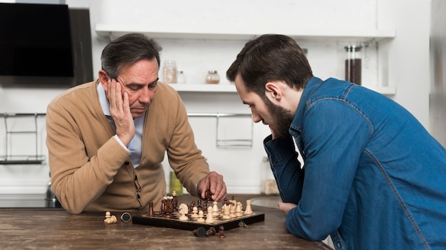 Photo gratuite père et fils jouant aux échecs à kithcen