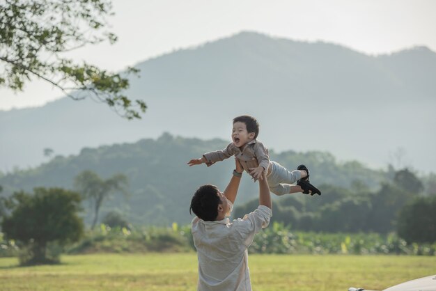 Père et fils jouant dans le parc à l'heure du coucher du soleil. les gens s'amusent sur le terrain. concept de famille sympathique et de vacances d'été.