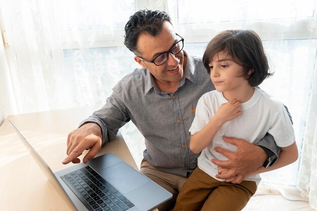 Père et fils jouant quelque chose sur un ordinateur portable