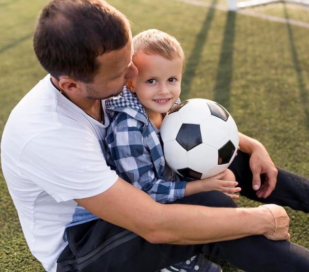 Photo gratuite père et fils jouant sur le terrain de football vue haute