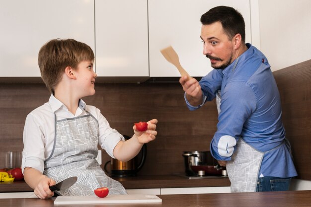 Père et fils jouent dans la cuisine pendant la cuisson