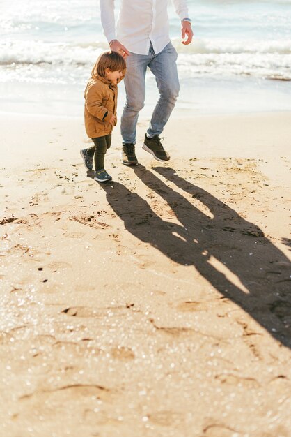 Père et fils sur la plage de sable jaune