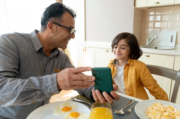 Photo gratuite père et fils regardant un smartphone à la maison