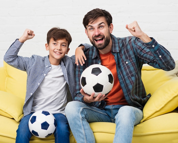 Père et fils tenant des ballons de football