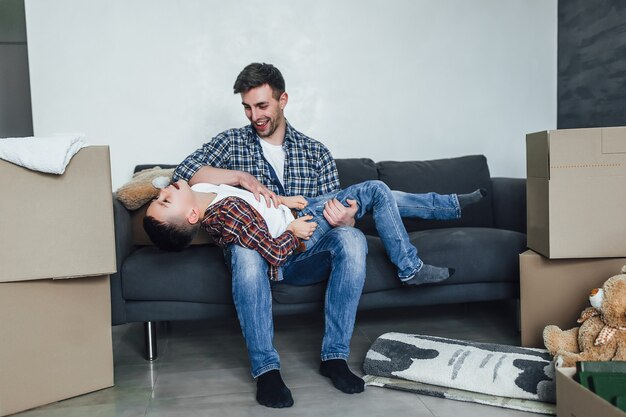 Père jouant avec son fils sur une nouvelle maison moderne. Émotions joyeuses