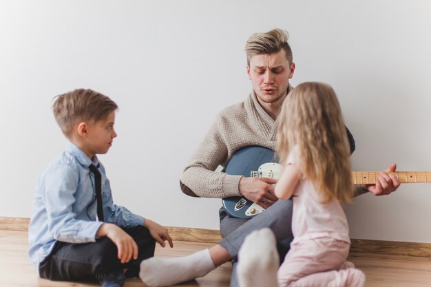 Père joue de la guitare avec ses enfants