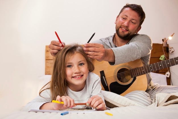 Père mettant des crayons sur la tête de sa fille