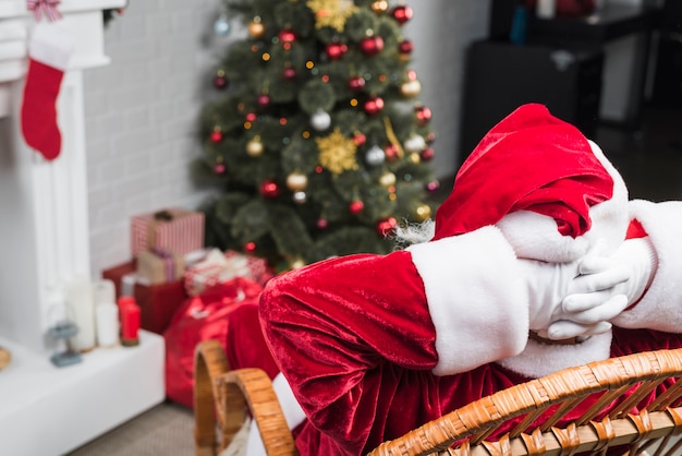 Père Noël assis sur une chaise berçante, mains derrière la tête