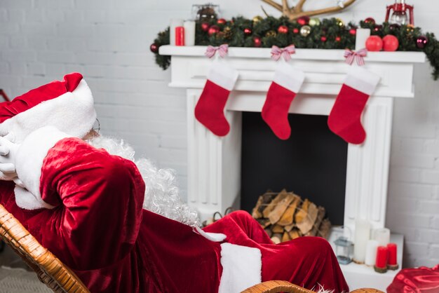 Père Noël assis sur une chaise berçante, mains derrière la tête