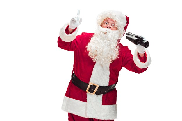Père Noël avec une barbe blanche luxueuse, un chapeau du père Noël et un costume rouge isolé sur fond blanc avec des jumelles