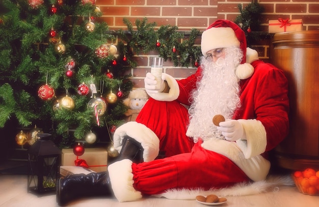 Père Noël Avec Des Cadeaux Assis à Côté D'un Arbre De Noël Photo Premium
