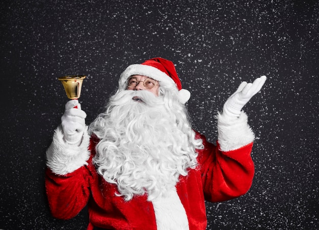 Photo gratuite père noël avec cloche parmi la neige qui tombe