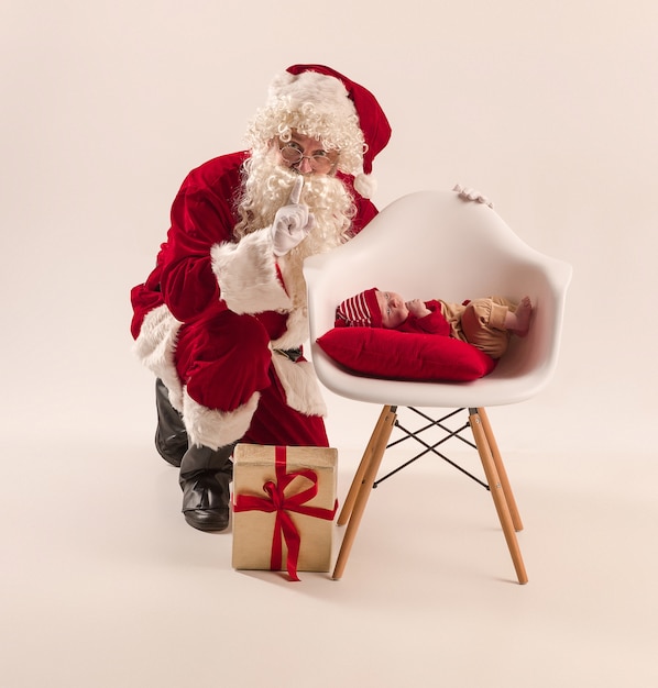 Père Noël en costume rouge avec un bébé isolé sur blanc