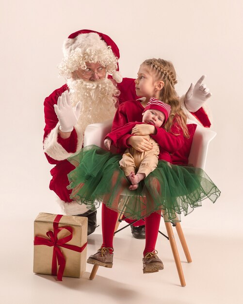 Père Noël en costume rouge avec une petite fille et un bébé isolé sur blanc