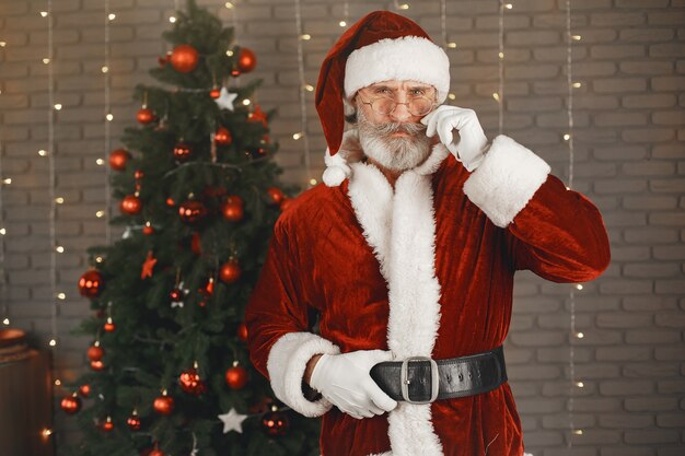 Père Noël debout près de l'arbre de Noël. Décoration d'intérieur.