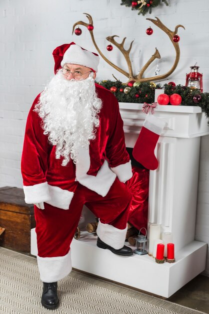 Père Noël debout près de la cheminée blanche