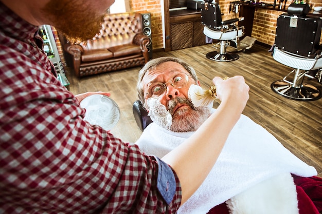 Photo gratuite père noël raser son barbier personnel