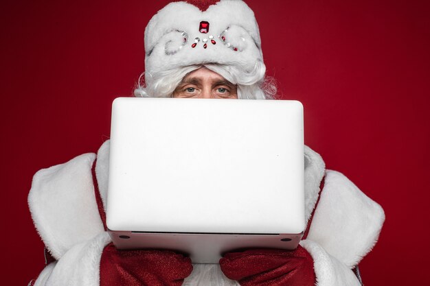 Père Noël se cachant derrière un ordinateur portable