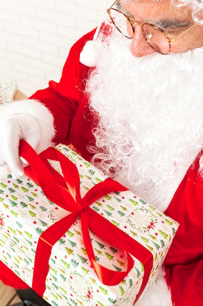 Photo gratuite père noël tenant dans les mains enveloppé de cadeau de noël