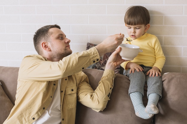 Photo gratuite père nourrit son fils dans le salon