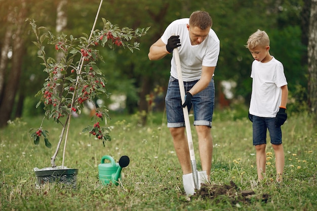 Photo gratuite père avec petit fils sont en train de planter un arbre sur une cour