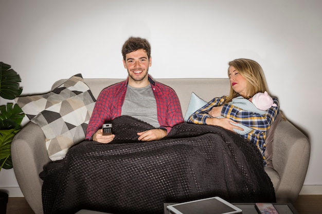 Photo gratuite père regarde la télévision pendant que la mère avec bébé dort