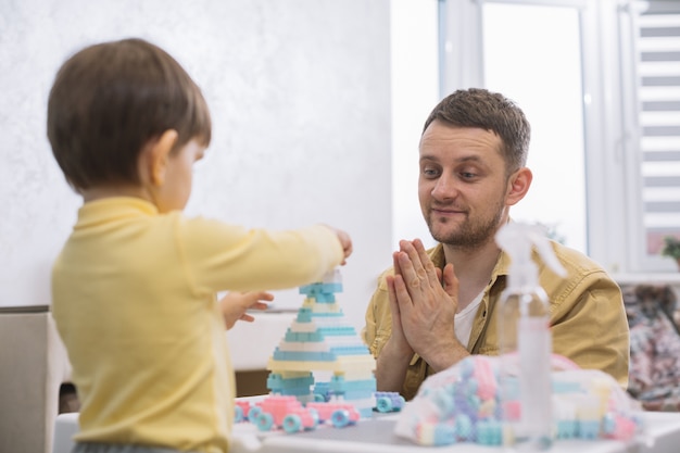 Photo gratuite père se concentrant sur les jouets de son fils