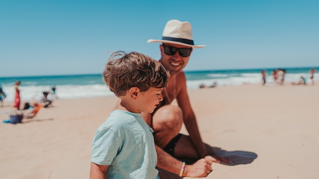 Père et son fils jouant joyeusement sur la plage de sable