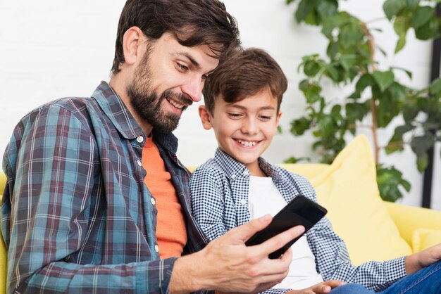 Père surpris et fils à la recherche au téléphone