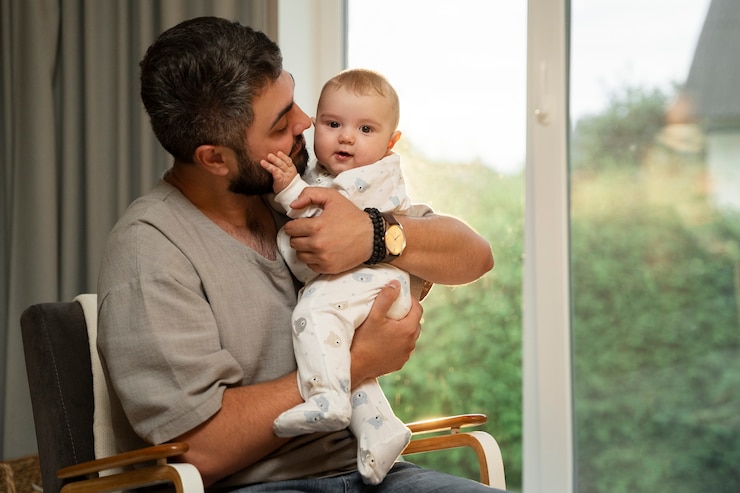 Photo gratuit père tenant bébé à la maison plan moyen
