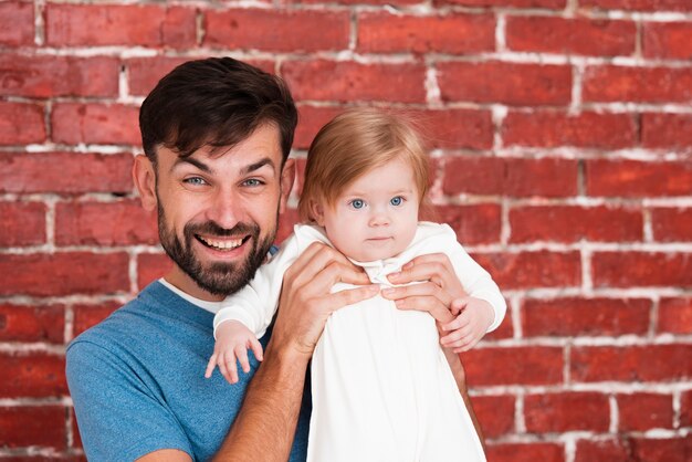 Père, tenue, bébé, brique, fond