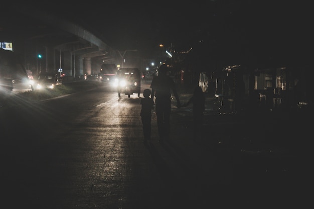 Père en train de marcher avec ses deux enfants la nuit dans la ville