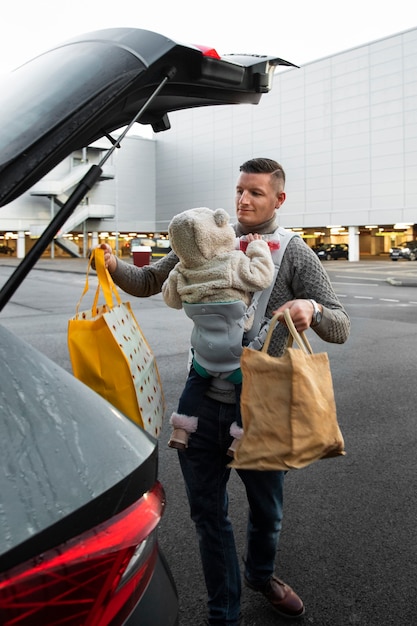 Photo gratuite père utilisant un porte-bébé pour son nouveau-né tout en faisant des activités quotidiennes