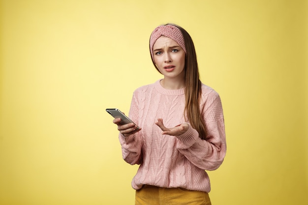 Perplexe confus bouleversé interrogé jeune fille mignonne en pull tricoté bandeau fronçant les sourcils désemparés rais...