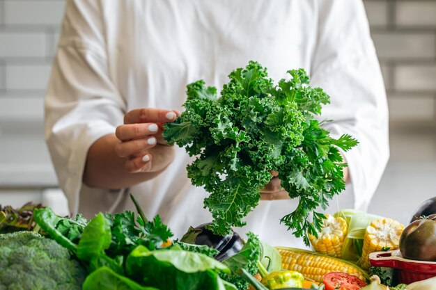 Persil et chou en gros plan dans les mains d'une femme dans la cuisine