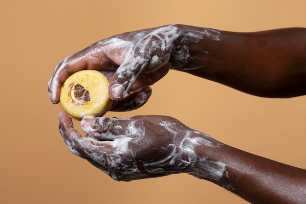 Photo gratuite personne africaine se lavant les mains avec du savon isolé sur orange