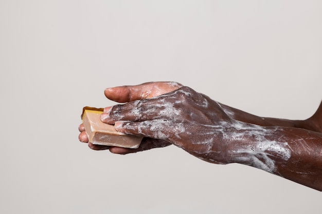 Personne africaine se laver les mains avec du savon isolé sur blanc