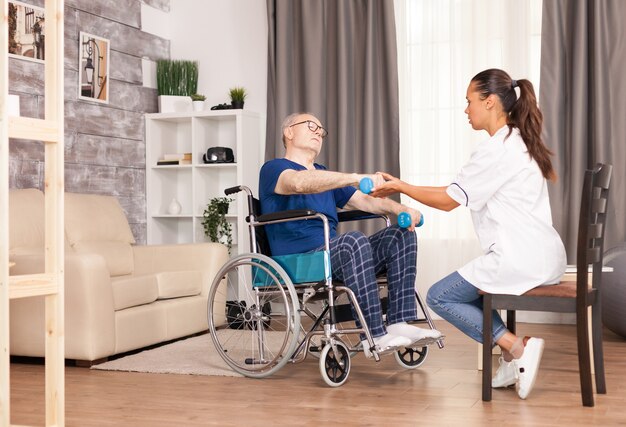 Personne âgée souffrant de douleurs aux bras assise sur un fauteuil roulant et s'entraînant avec des haltères