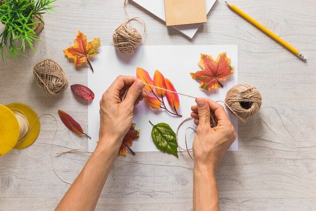 Une personne à l&#39;aide de ficelle d&#39;automne faux feuilles sur fond en bois