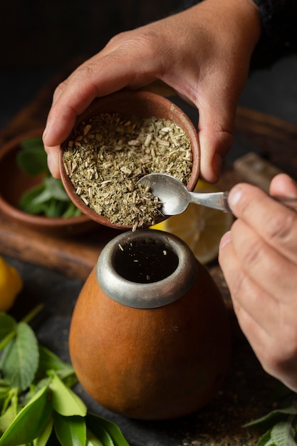 Personne à angle élevé ajoutant des herbes dans l'infuseur