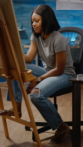 Personne artistique noire concevant un chef-d'œuvre de vase sur une table dans un espace d'œuvres d'art. Jeune femme afro-américaine créant un dessin moderne pour un projet d'art professionnel. Adulte avec créativité