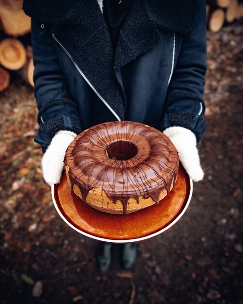 Personne en blazer noir tenant une tasse en céramique marron et blanche