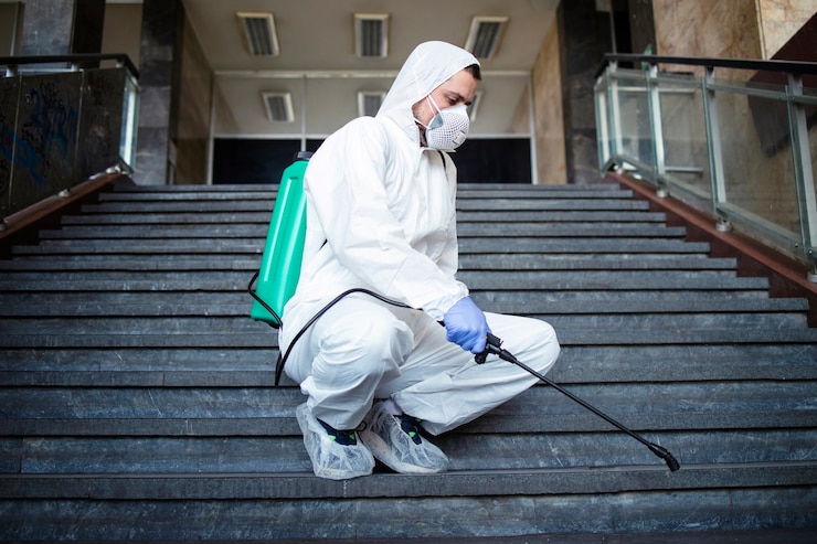 Photo gratuit personne en combinaison de protection chimique blanche désinfectant les couloirs publics et mesures pour arrêter la propagation du virus corona très contagieux